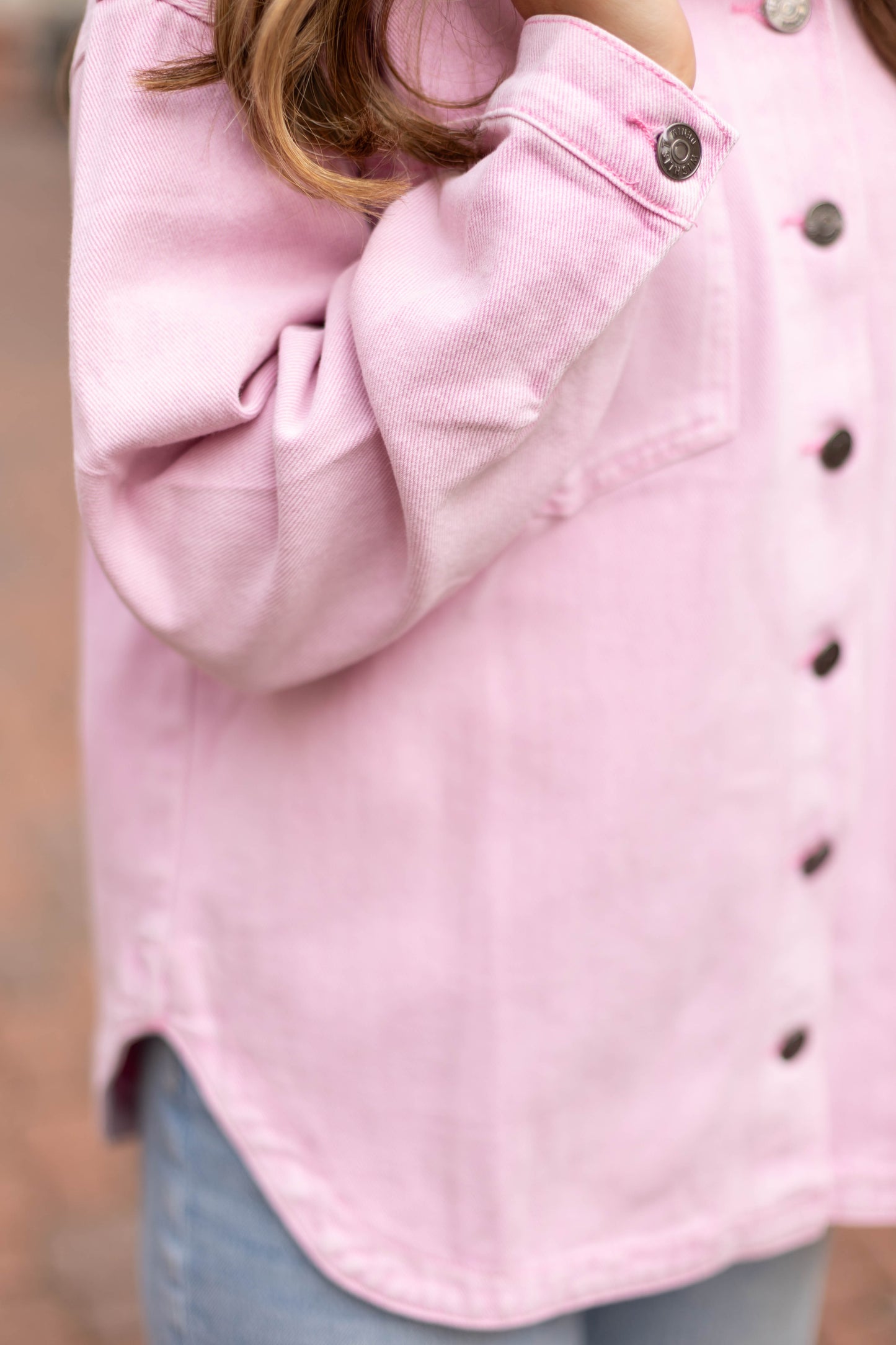 A person wears the Dogwood Cloth Leah Denim Jacket over a light pink button-up and light blue jeans, with long brown hair visible, standing outdoors.